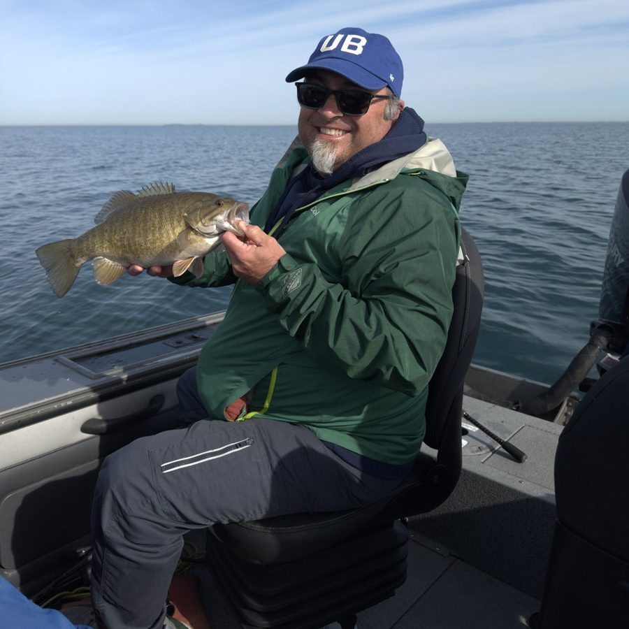 Dr. Pericak holding a smallmouth bass on a boat