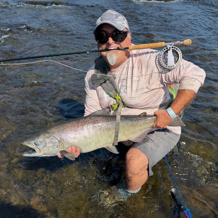 Dr. Pericak holding a salmon while wading in a river